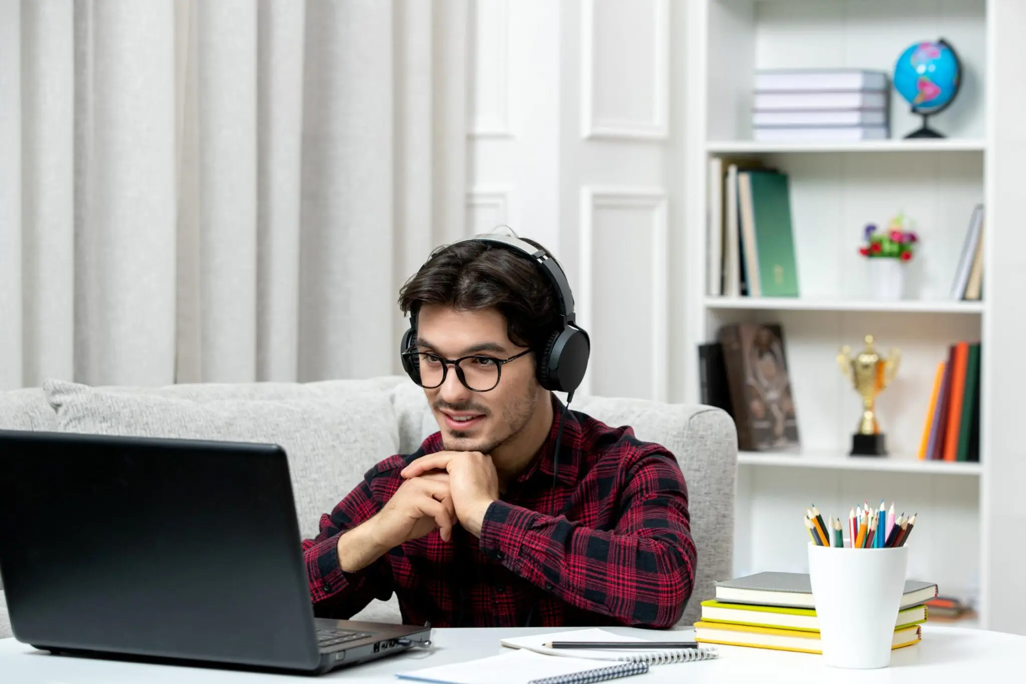 A man with headphones sits at a desk in pk12 virtual academy, focused on his laptop while working or studying